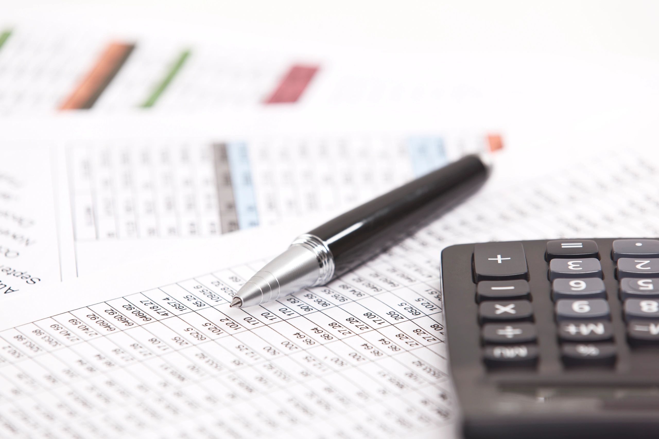 Tax forms, calculator, and pen on a desk